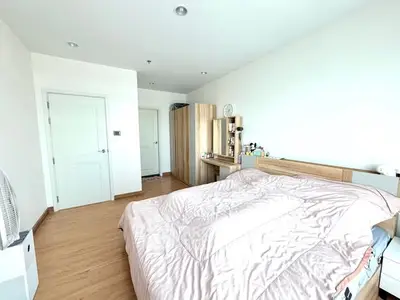 Spacious bedroom with wooden flooring and modern furnishings in a bright apartment.