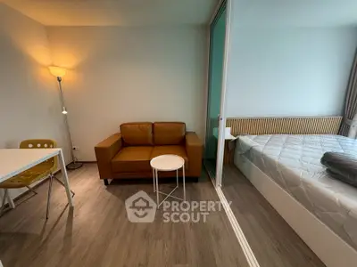 Modern studio apartment with cozy living area and bedroom separated by glass partition.