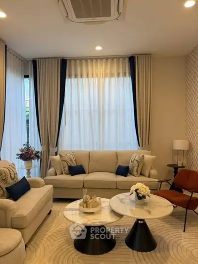 Elegant living room with plush sofas, stylish decor, and natural light