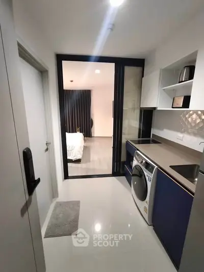 Modern kitchen with sleek appliances and open layout leading to a cozy bedroom.