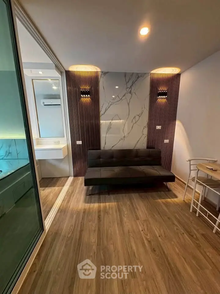Modern living room with stylish decor and wooden flooring, featuring a sleek sofa and ambient lighting.