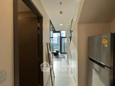 Modern apartment hallway leading to a bright living room with stunning city view.