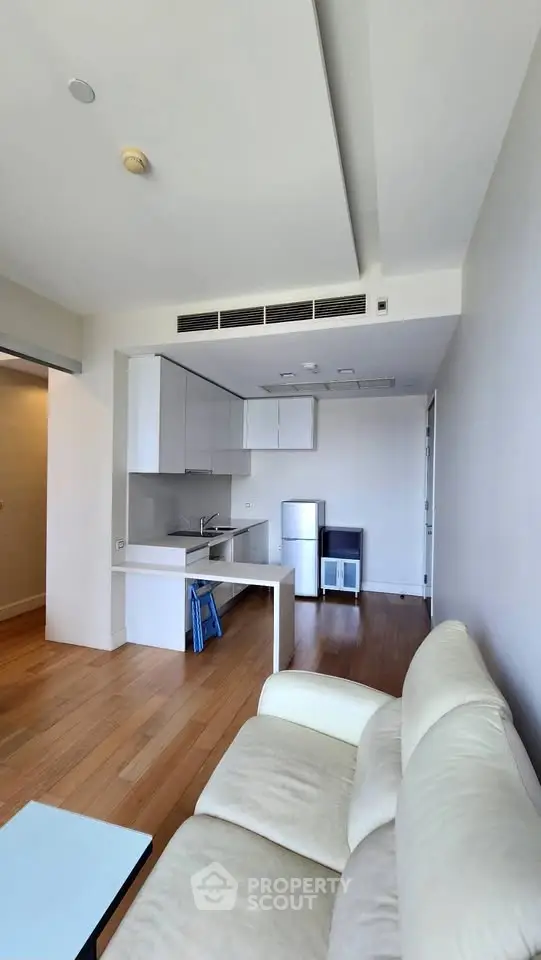 Modern open-layout living room with sleek kitchen and cozy seating area, perfect for urban living.