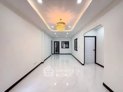 Spacious modern living room with elegant chandelier and glossy white flooring.