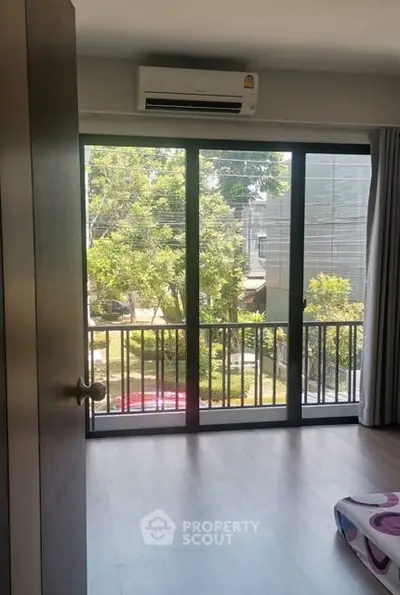 Spacious room with large windows and balcony overlooking lush greenery