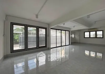 Spacious modern living room with large windows and glossy tiled floors, perfect for natural light and open living.