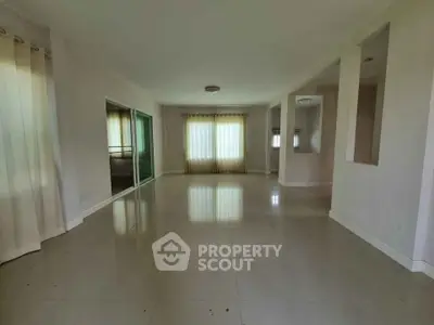 Spacious empty living room with large windows and glossy tiled floors