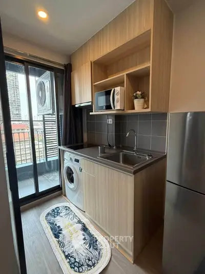 Modern compact kitchen with washing machine and balcony view in urban apartment