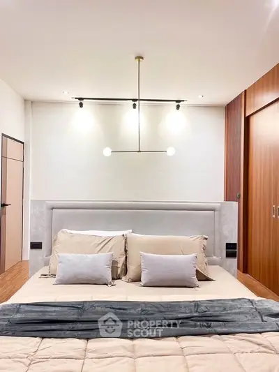 Modern bedroom with stylish lighting and cozy bedding in a contemporary home.