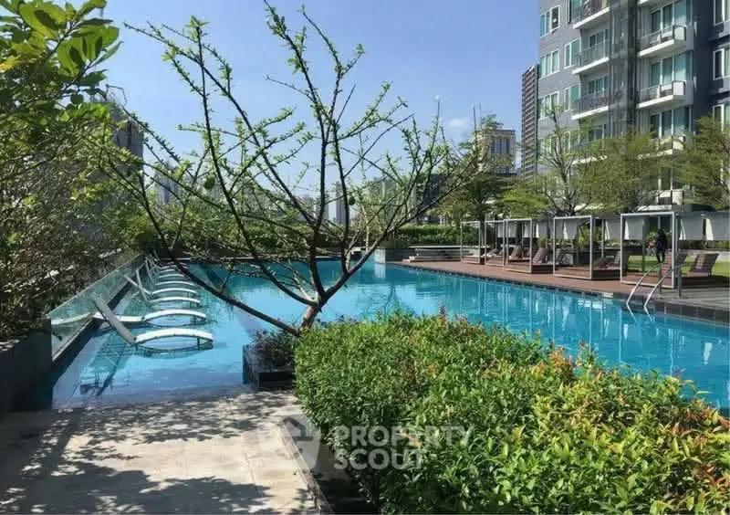 Luxurious residential pool area with sun loungers and lush greenery, perfect for relaxation and leisure.