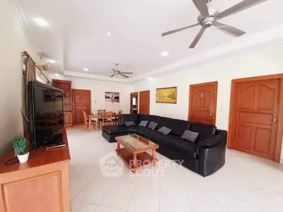 Spacious living room with modern black sofa and ceiling fans, perfect for family gatherings.