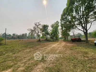 Expansive rural land with lush greenery and a rustic tractor, perfect for development or agriculture.