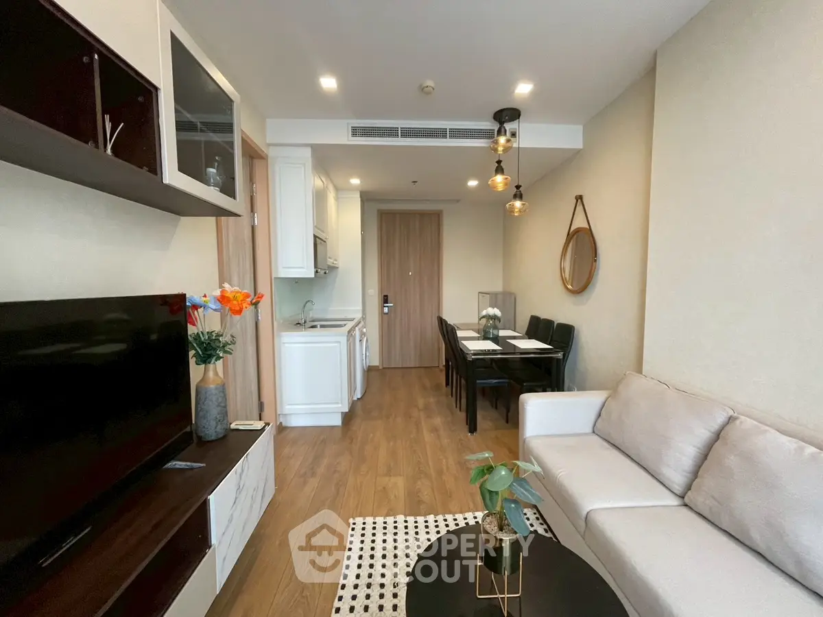 Modern living room with open kitchen, stylish decor, and cozy seating area in a contemporary apartment.
