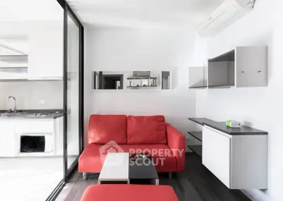 Modern living room with red sofa and sleek kitchen in open layout apartment.