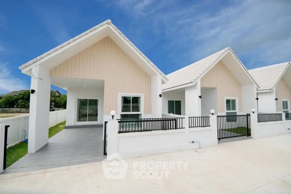 Charming modern single-story homes with white facades and gabled roofs under a clear blue sky.