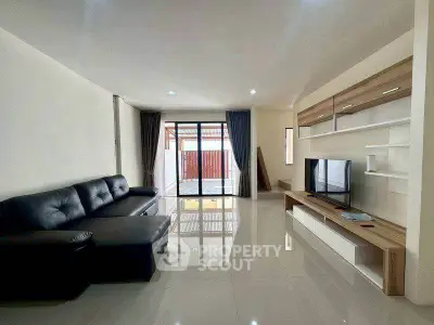 Spacious modern living room with sleek black sofa and large TV unit, perfect for relaxation.