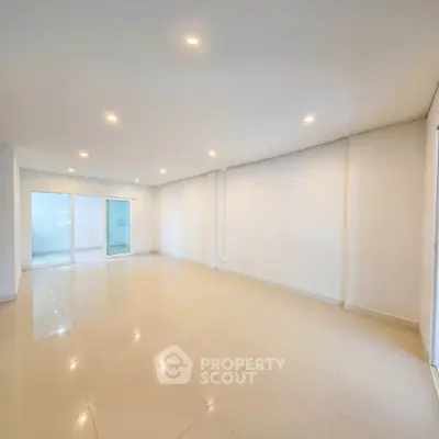 Spacious empty living room with bright lighting and sliding glass doors.