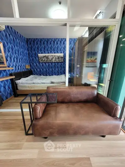 Modern apartment with stylish living room and cozy bedroom separated by glass wall, featuring chic decor.