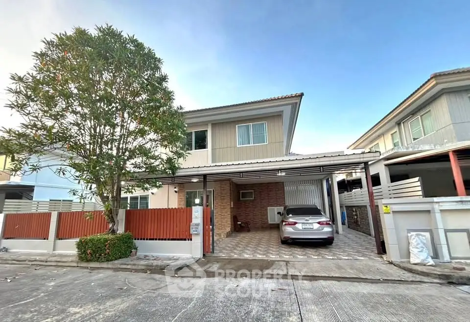 Charming two-story house with carport and tree-lined driveway in suburban neighborhood.