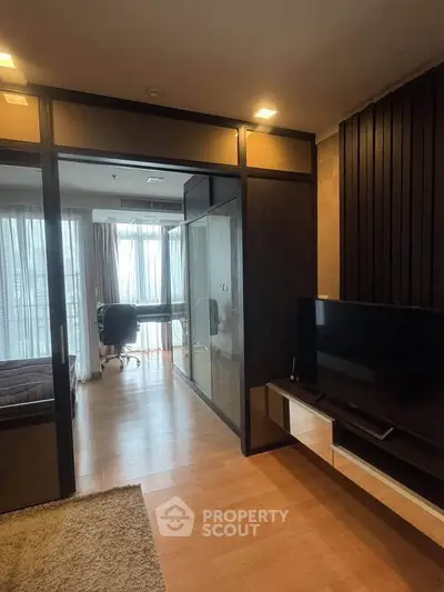 Modern apartment interior with cozy living room and study area, featuring wooden flooring and natural light.