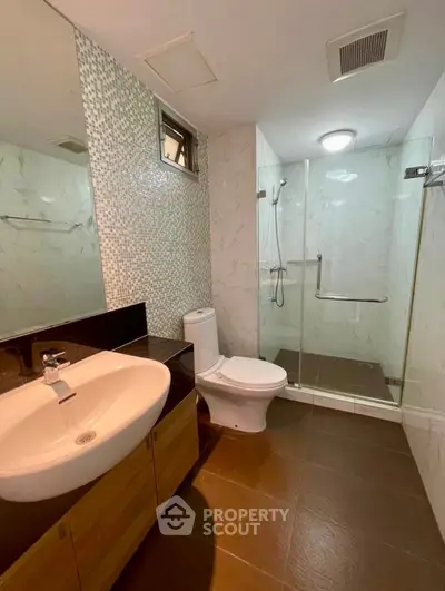 Modern bathroom with glass shower and stylish sink in contemporary apartment.