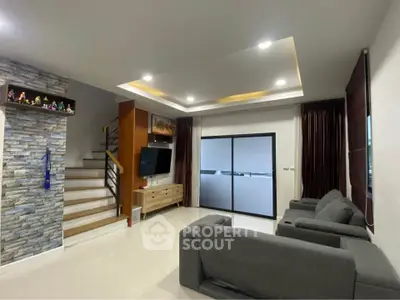 Modern living room with stylish decor and staircase, featuring sleek furniture and ambient lighting.