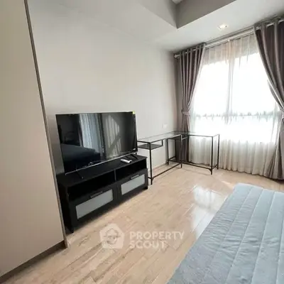 Modern bedroom with TV and large window, featuring elegant curtains and sleek furniture.