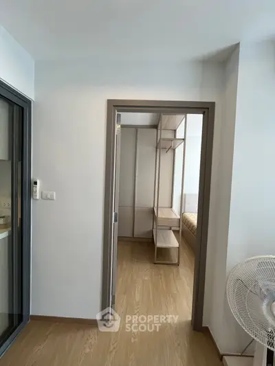 Modern apartment interior with wooden flooring and a view into a cozy bedroom