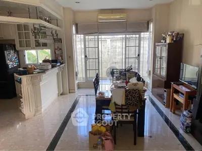 Spacious living room with dining area and open kitchen, featuring elegant marble flooring and large windows.