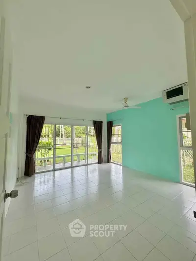 Spacious living room with large windows and garden view, perfect for natural light lovers.