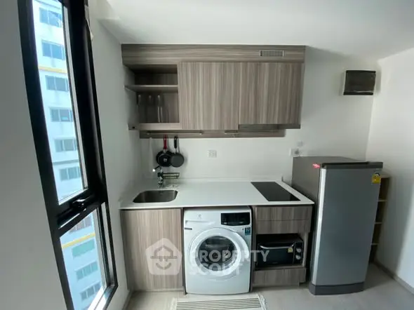 Modern compact kitchen with washing machine and fridge in a stylish apartment.