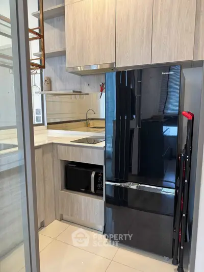 Modern kitchen with sleek black fridge and minimalist cabinetry design.
