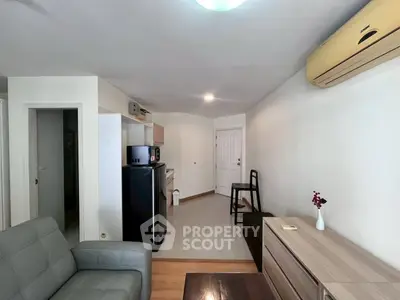 Cozy living room with modern furniture and compact kitchen in open layout apartment.