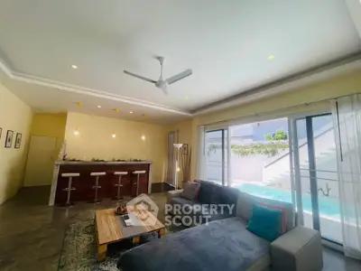 Spacious living room with modern open kitchen and pool view, perfect for entertaining.