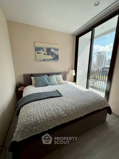 Modern bedroom with large window and city view, featuring cozy bedding and stylish decor.