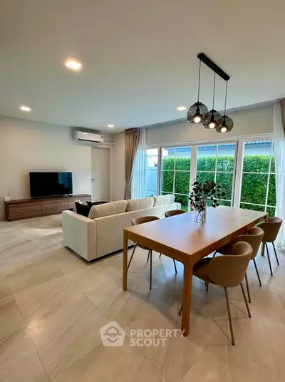 Spacious modern living room with elegant dining area and large windows offering garden views.