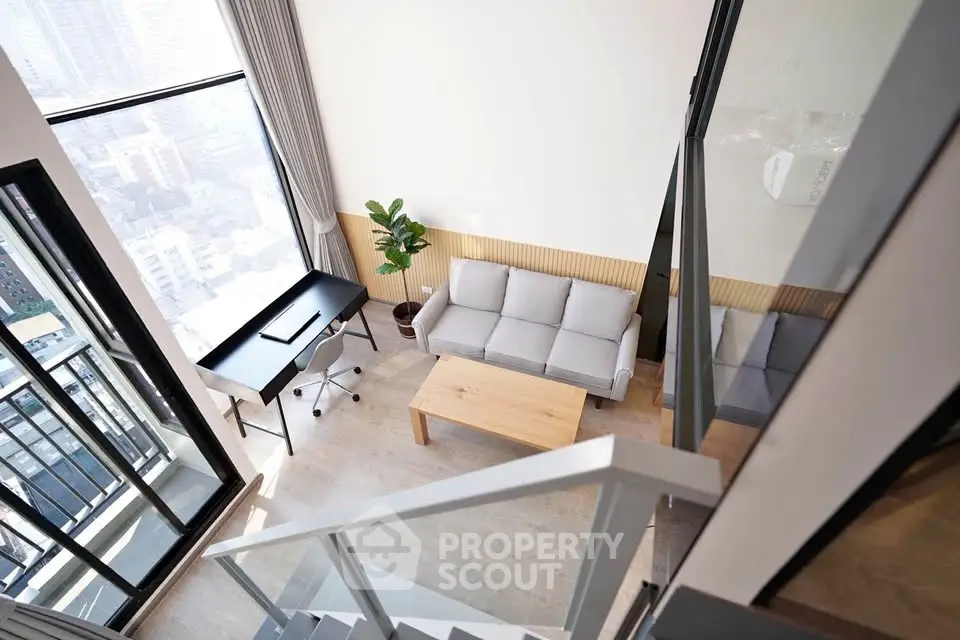 Modern loft apartment with large windows and stylish furniture, featuring a cozy living area and workspace.