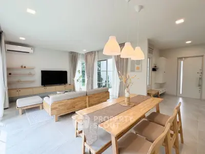 Spacious modern living room with dining area, featuring elegant wooden furniture and natural light.