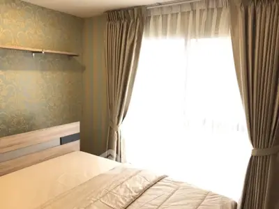 Cozy bedroom with elegant wallpaper and large window with curtains, perfect for relaxation.