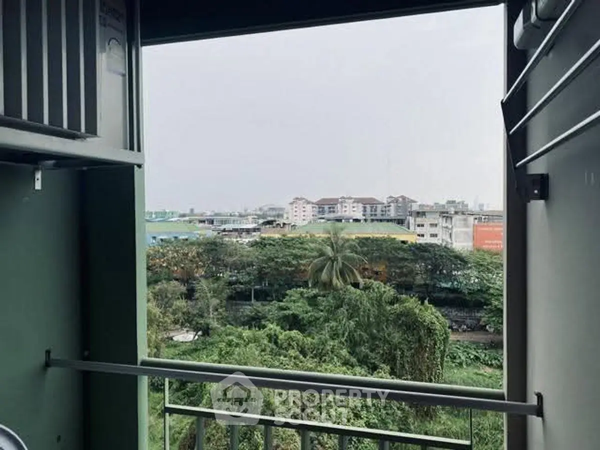 Scenic view from a balcony overlooking lush greenery and distant buildings.