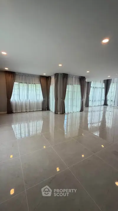 Spacious modern living room with large windows and elegant curtains, perfect for natural light lovers.