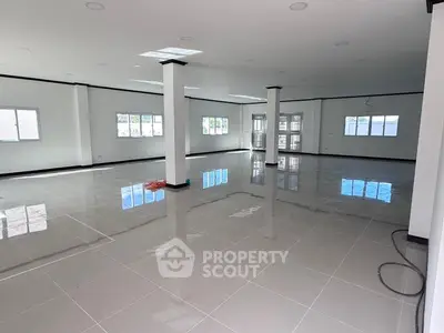 Spacious open-plan interior with glossy tiled floors and ample natural light, ideal for versatile use.