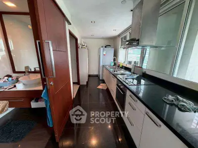 Modern kitchen with sleek black countertops and stainless steel appliances in a contemporary apartment.