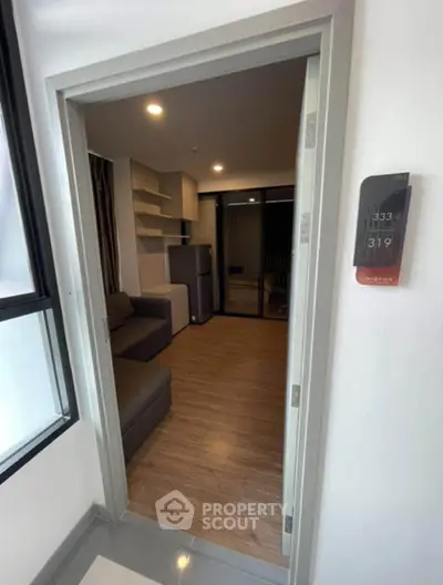 Modern apartment entrance with cozy living room and sleek wooden flooring.