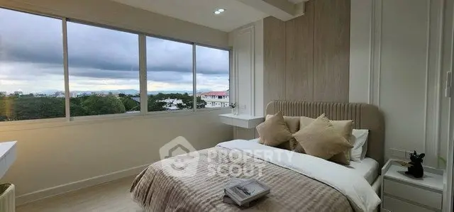 Elegant bedroom with large windows offering a stunning view, featuring cozy bedding and modern decor.