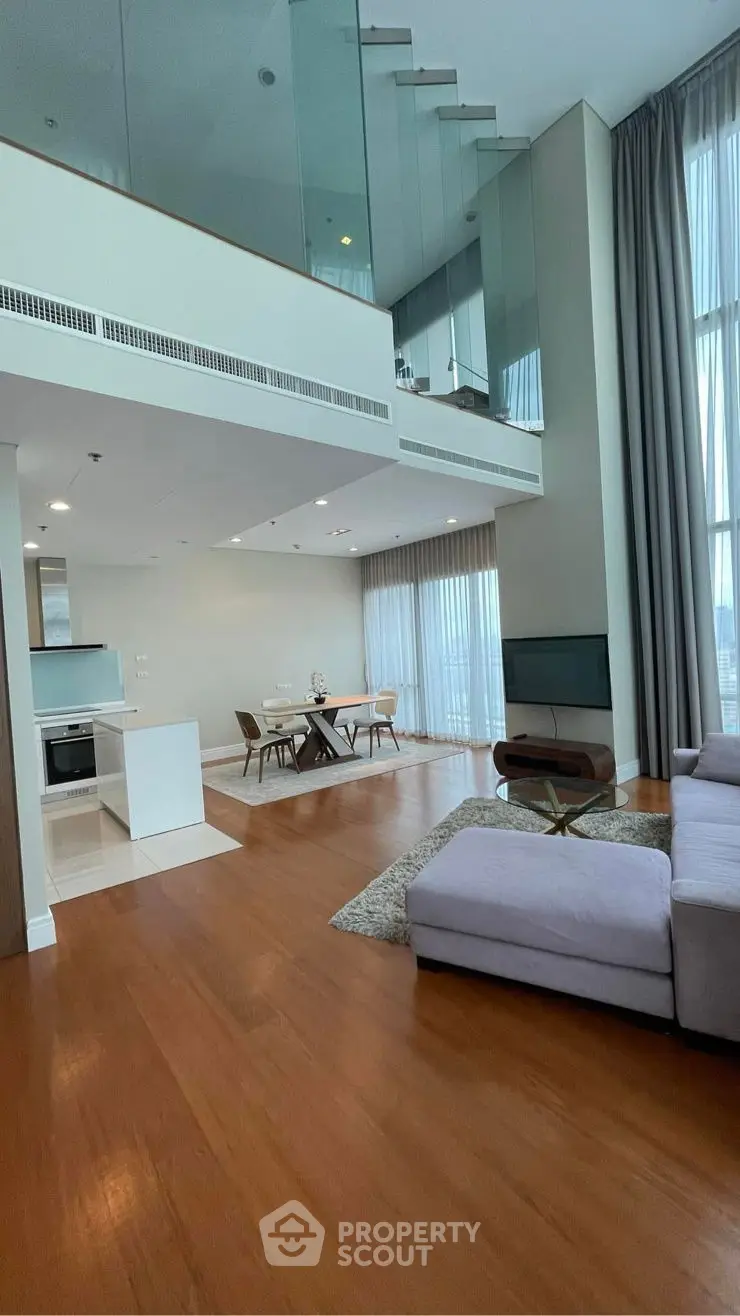 Luxurious modern living room with high ceilings and mezzanine, featuring open layout and elegant decor.