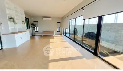 Spacious sunlit room with large windows and modern decor