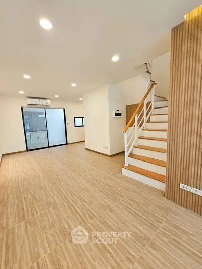 Spacious modern living room with wooden flooring and staircase in a stylish home.