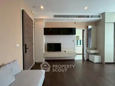 Modern living room with sleek design and wooden flooring, featuring a wall-mounted TV and stylish furniture.