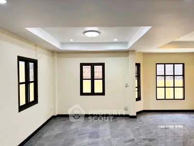 Spacious unfurnished living room with large windows and modern ceiling lights.